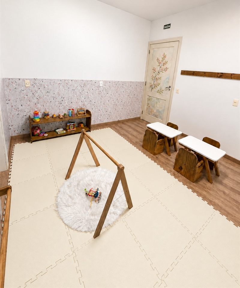 Sala do Programa Materna: tapete de espuma claro com ginásio de madeira para bebês, prateleira de brinquedos e mesinhas baixas